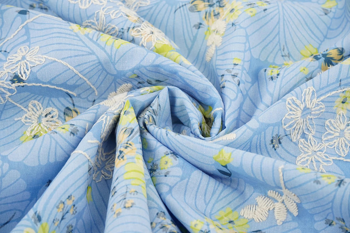 Attēls ar Izšūts kokvilnas audums - dzetenas puķes uz zila 115 g/m² – pieejams Šarlotes audumi