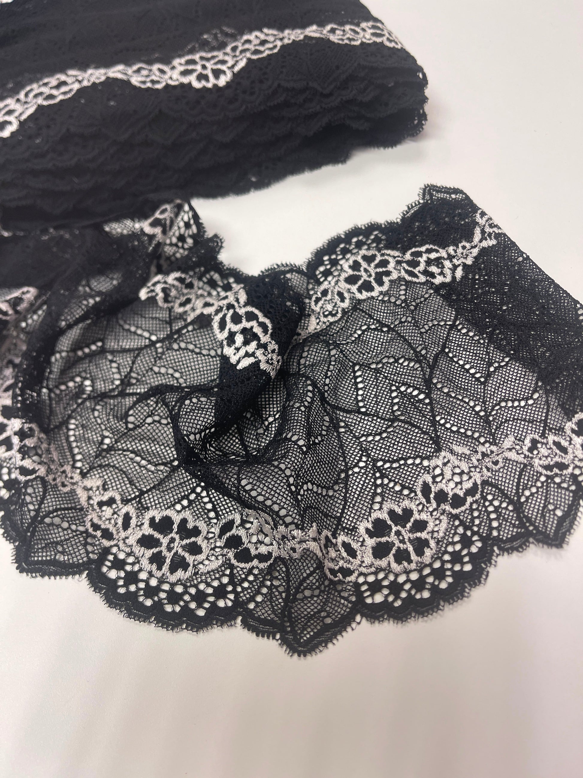 Image of elastic lace 18 cm, black with white flowers – available online at Šarlotes audumi