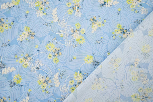 Attēls ar Izšūts kokvilnas audums - dzetenas puķes uz zila 115 g/m² – pieejams Šarlotes audumi