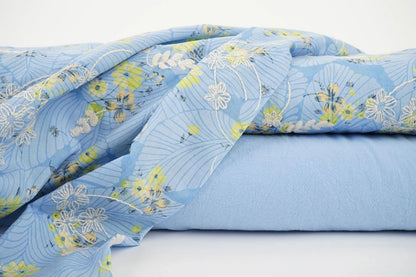 Image de tissu en coton brodé - fleurs jaunes sur fond bleu 115 g/m² – disponible chez Šarlotes audumi