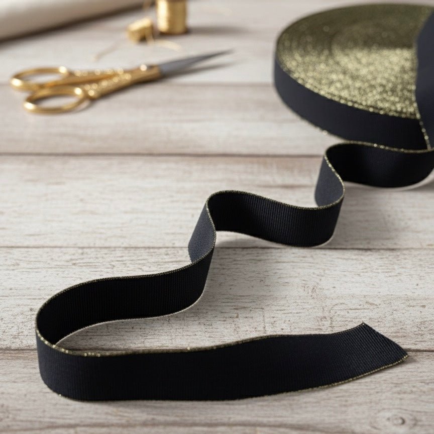 Attēls ar Plakanā gumija - 2,5 cm melna ar zelta maliņu – pieejams Šarlotes audumi